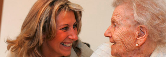 Auf dem Bild sieht man ein fröhliches Gespräch zwischen einer Mitarbeiterin und einer älteren Bewohnerin.